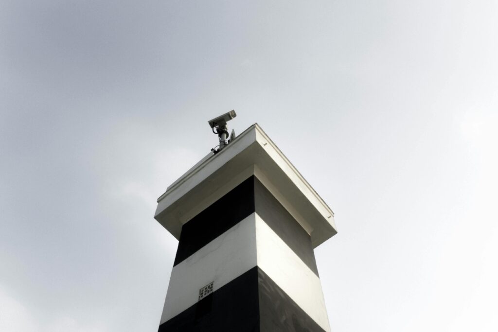 A modern surveillance tower equipped with a CCTV camera against a clear sky, showcasing security and technology.